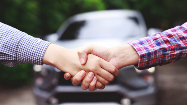 Zwei Personen geben sich vor einem Auto die Hand, symbolisiert eine Einigung oder Kaufabschluss. Durch anklicken gelangt man zum Inzahlungnahme-Formular. 